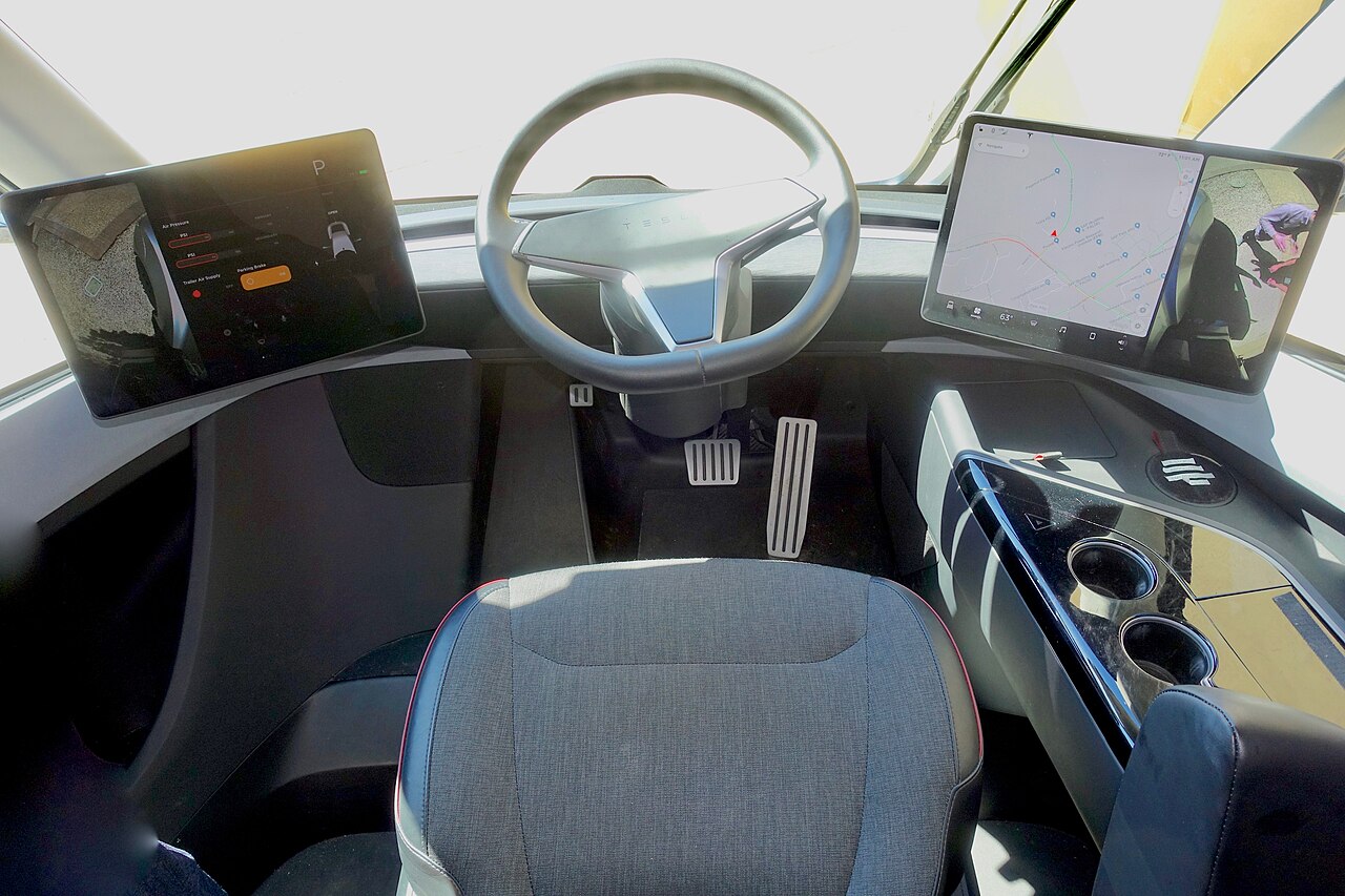 스티어링 휠 좌우로 듀얼 스크린이 배치되고 중앙에 1인승 시트가 위치한 테슬라 세미 실내 인테리어